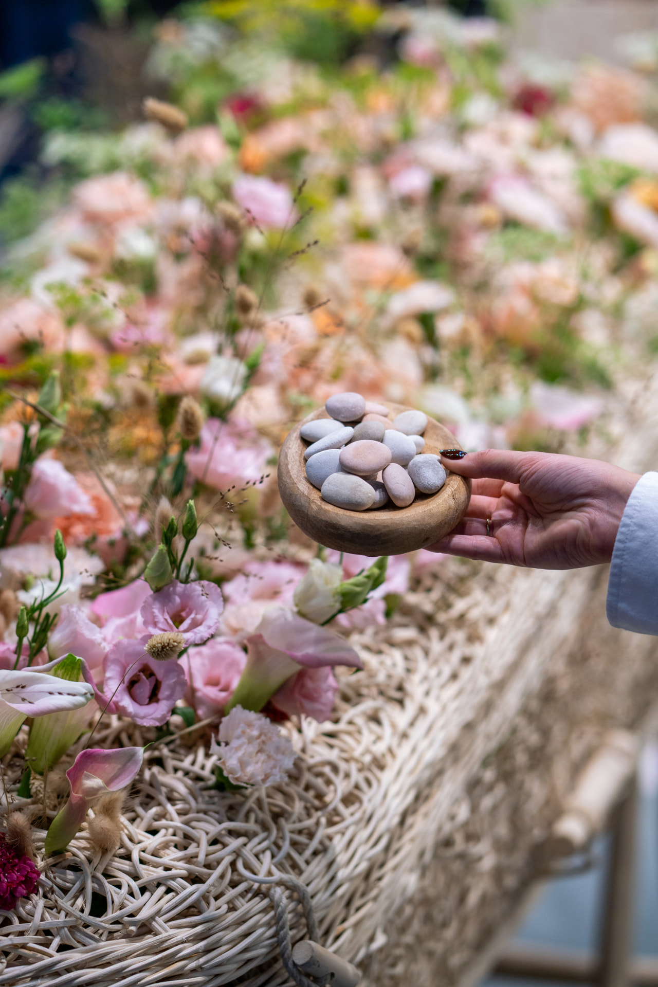 Een houten schaaltje met steentjes tussen bloemen bij een kist